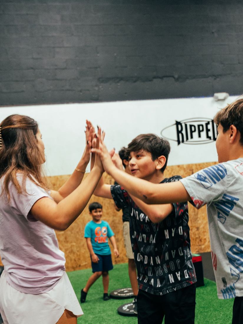 Kids high-fiving a coach at Ripped Kids